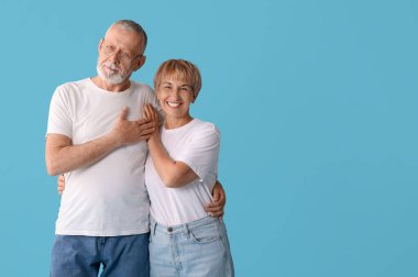 Mutlu olgun çift mavi arka planda sarılıyor.