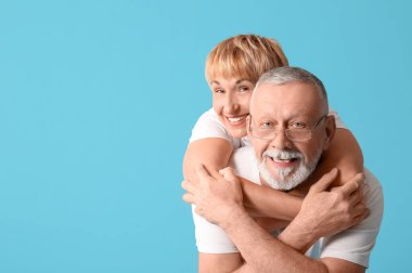 Mutlu olgun çift mavi arka planda sarılıyor.
