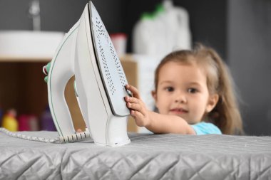 Küçük şirin kız banyoda demire dokunuyor. Tehlikedeki çocuk