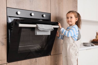 Mutfakta elektrikli fırın açan tatlı küçük kız. Tehlikedeki çocuk