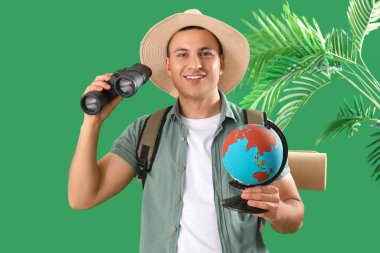 Yeşil arka planda dürbünü olan erkek turist