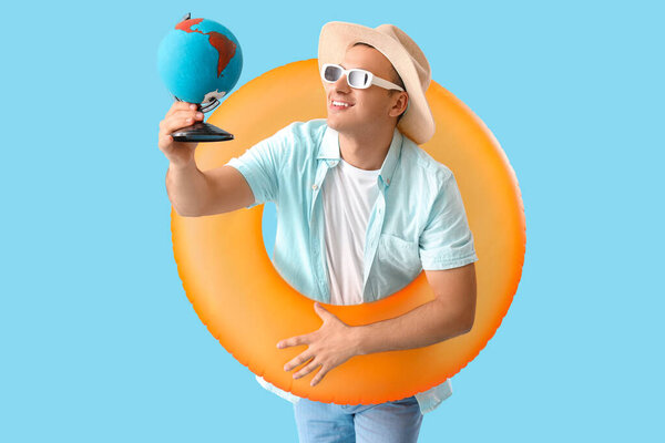 Мужской турист с земным шаром и плавательным кольцом на синем фоне