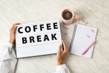 Kadın eli, arka planda açık kahve kırığıyla tahtayı tutuyor.