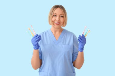Mavi arka planda diş fırçası olan kadın dişçi.