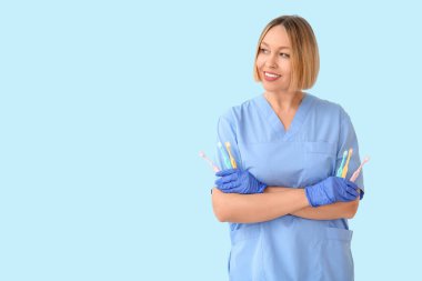 Mavi arka planda diş fırçası olan kadın dişçi.