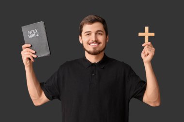 Kutsal kitapla gülümseyen adam ve siyah arka planda haç