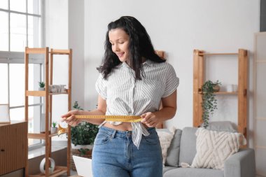 Evinde belini ölçen genç ve güzel bir kadın. Kilo verme konsepti