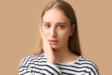 Kahverengi arka planda diş ağrısı çeken güzel bir genç kadın.