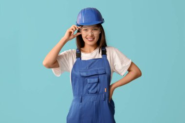 Mavi arka planda koruyucu giysileri olan genç bayan işçi.