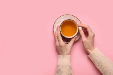 Kadın eli, arka planda yeşil çay bardağını tutuyor
