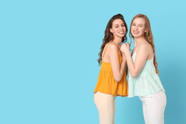 Mavi arka planda el ele tutuşan güzel kız kardeşler.