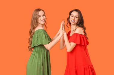 Turuncu arka planda güzel genç kız kardeşler