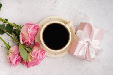 İçinde güzel güller ve beyaz arka planda bir fincan kahve olan hediye kutusu.