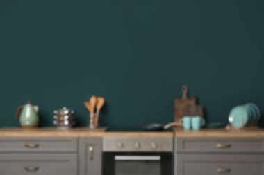 Gri tezgahlı, fırınlı ve yeşil duvarlı modern mutfağın bulanık manzarası