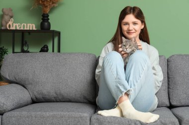 Evdeki kanepede sevimli gri kedisi olan genç bir kadın.