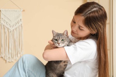 Evde sevimli gri kedisi olan genç bir kadın var.