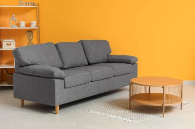 Siyah kanepesi, sehpası ve turuncu duvarı olan şık bir oturma odası.