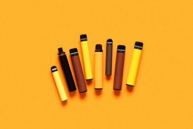 Turuncu arka planda farklı elektronik sigaralar.