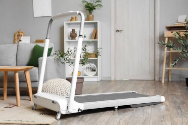 Modern treadmill in interior of light living room