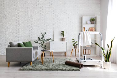 Koşu bandı, bitki ve kanepesi olan aydınlık oturma odasının içinde.