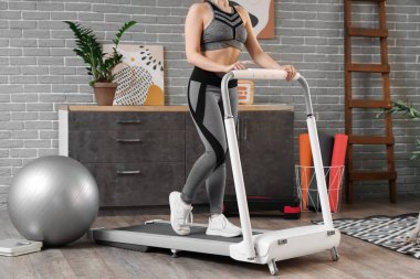Spor kadın evde koşu bandında antrenman yapıyor.
