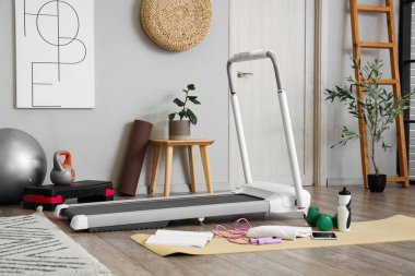 Koşu bandı ve spor ekipmanlarıyla ışık odasının içinde.