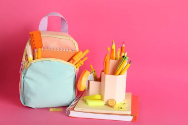 Pembe arka planda kırtasiyeli okul çantası.