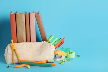 Mavi zemin üzerinde kırtasiye malzemesi olan kitaplar ve kalem kutusu