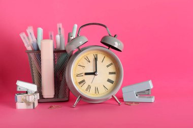 Pembe arka planda çalar saat ve okul malzemeleri