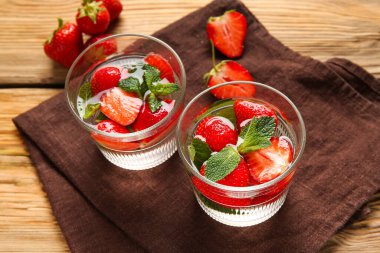 Çilekli ve ahşap arkaplanda naneli su bardakları.