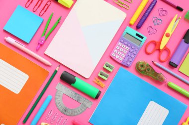 Pembe arka planda not defterleri ve kırtasiye malzemeleri