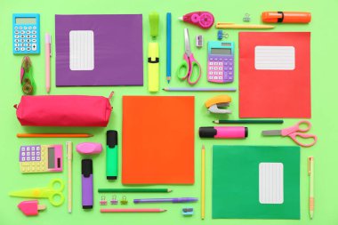 Yeşil arka planda not defterleri ve kırtasiye malzemeleri