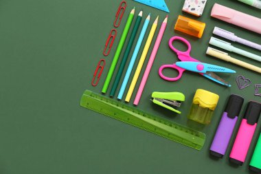 Yeşil arkaplanda farklı kırtasiye malzemesi olan kompozisyon