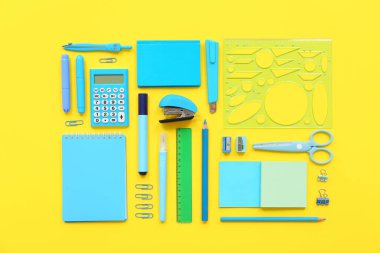 Sarı zemin üzerinde farklı kırtasiye malzemesi olan kompozisyon