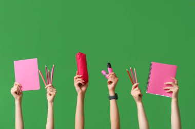 Yeşil zemin üzerinde kırtasiye, defter ve kalem kutusu olan birçok el