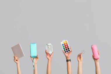 Gri arkaplanda kum saati, palet ve kalem kutuları olan birçok el.