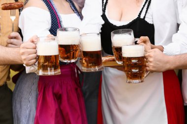 Geleneksel Alman kıyafetleri içinde gençler bira ve sosislerle Ekim Festivali 'ni dışarıda kutluyorlar.