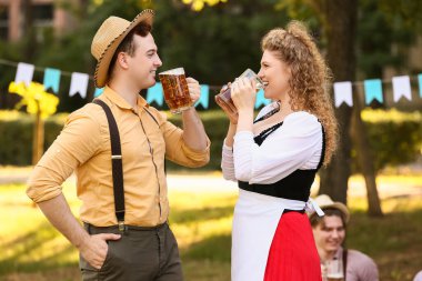 Geleneksel Alman kıyafetleri içinde dışarıda bira içen genç bir çift. Ekim Festivali Kutlaması