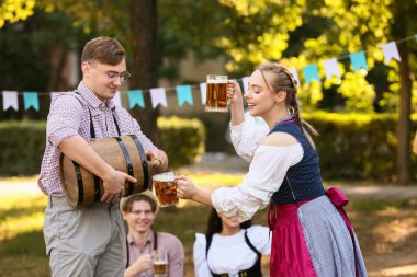 Geleneksel Alman kıyafetleri içindeki gençler ve bira fıçısı Ekim Festivali 'ni dışarıda kutluyorlar.