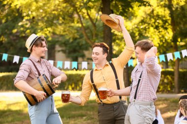 Geleneksel Alman kıyafetleri içinde genç erkekler ve bira Ekim Festivali 'ni dışarıda kutluyorlar.