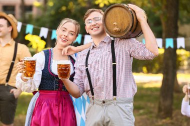 Geleneksel Alman kıyafetleri içinde genç bir çift, bir fıçı birayla Ekim Festivali 'ni dışarıda kutluyor.
