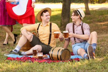 Geleneksel Alman kıyafetleri içinde açık havada bira içen genç adamlar. Ekim Festivali Kutlaması