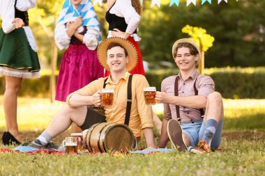 Geleneksel Alman kıyafetleri içinde açık havada bira içen genç adamlar. Ekim Festivali Kutlaması