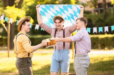 Geleneksel Alman elbiseli gençler bira ve Bavyera bayrağıyla Ekim Festivali 'ni dışarıda kutluyorlar.