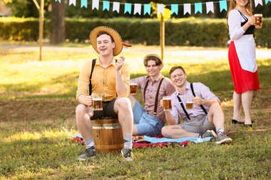 Geleneksel Alman kıyafetleri içinde, bira ve sosisli genç adam Ekim Festivali 'ni dışarıda kutluyor.