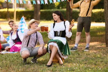 Geleneksel Alman kıyafetleri içinde genç bir çift bira ve krakerle Ekim Festivali 'ni dışarıda kutluyor.