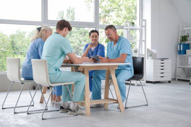 Klinikteki masada röntgen görüntülerini inceleyen bir grup doktor.