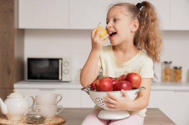 Mutfakta elmaları olan tatlı küçük bir kız.