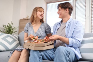 Lezzetli pizzaları alıp oturma odasındaki kanepede oturan genç ve güzel bir çift.