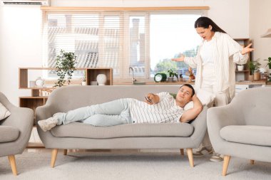 Kocasıyla kavga eden genç bir kadın evde televizyon seyrediyor.